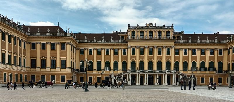 Schloss Schönbrunn in Wien. Ein großer ockergelber Palast von vorne
