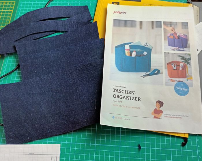 Zuschnitt aus blauem Filz und das Pattydoo-Schnittmuster für den Organizer auf einem Tisch.
