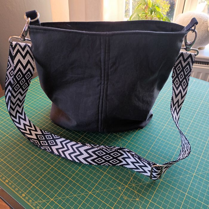 Selbstgenähte Tasche Annie aus dunkelblauem Oilskin als Flatlay auf dem Tisch.