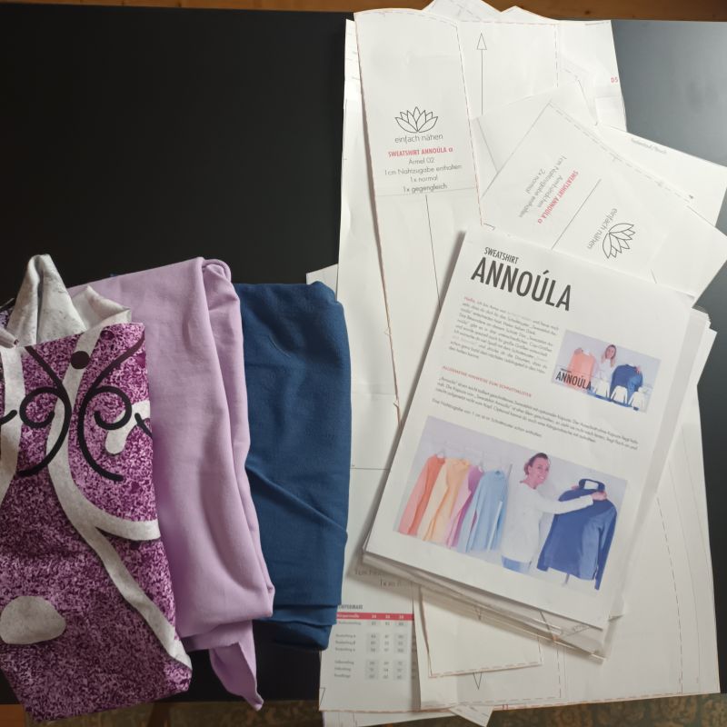 Schnittmuster Annóula, Beschreibung und Stoffauswahl fürs Probestück auf dem Tisch ausgebreitet.